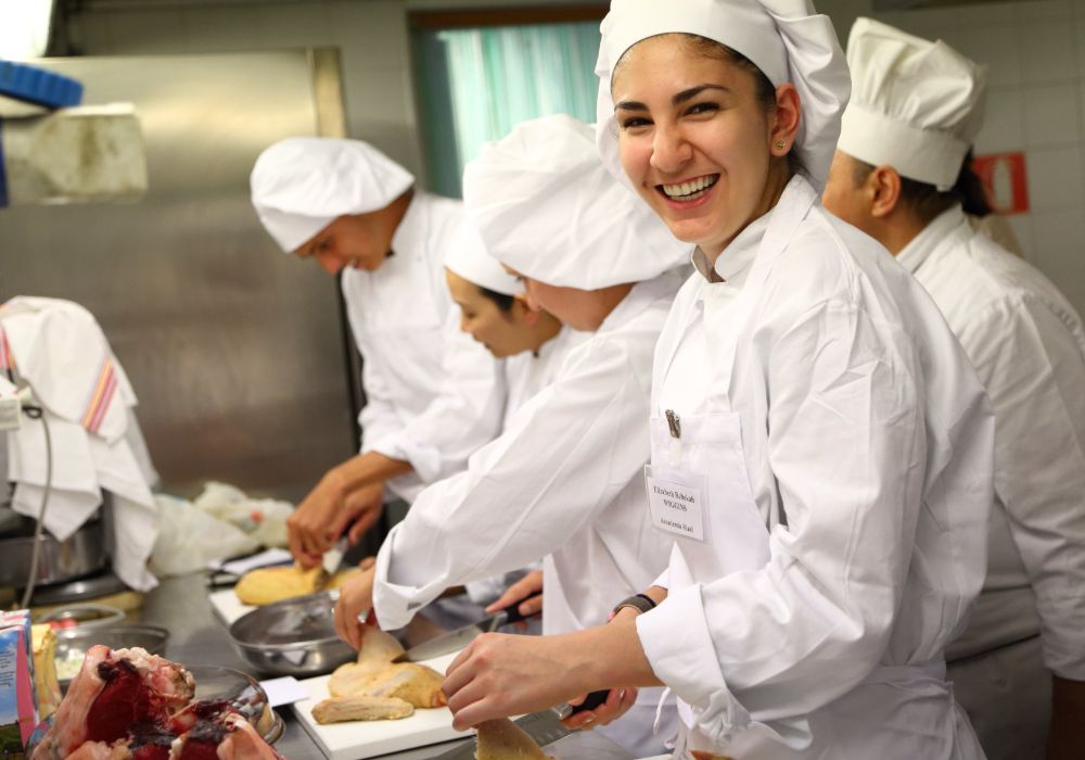 A group of smiling chefs in white uniforms standing together.