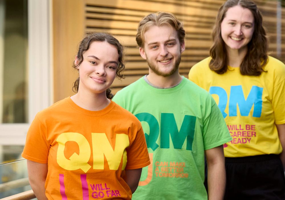 Three students in shirts featuring "QM," representing Queen Margaret University in Scotland.